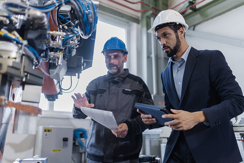 OSHA safety consultant and mechanic worker doing on-site consultation in industrial factory