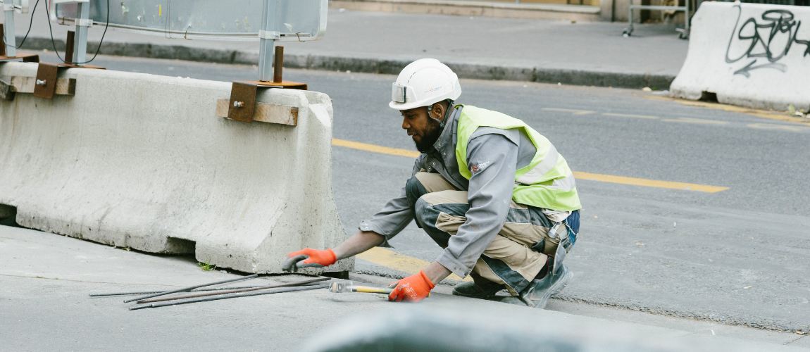 Road construction worker in a hard hat, placing concrete barriers