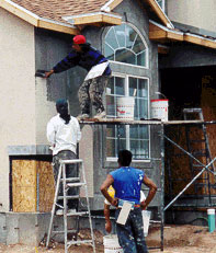 Workers working on the outside of a house without wearing hardhats
