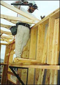 Figura 1 - Trabajador instalando armaduras de techo desde un andamio de soporte interior.