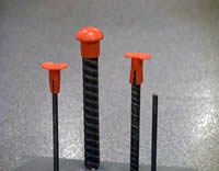Three different sizes of steel rebar with red mushroom-style plastic caps